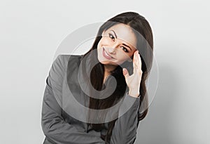 Beautiful smiling business woman in suit holding the hands under the face and looking up on blue background. Closeup studio