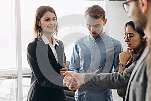 Beautiful smiling businesswoman and businessman handshaking standing in office, nice to meet you, first impression, being promoted