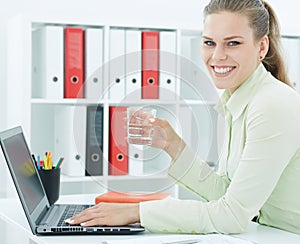 Beautiful smiling businesswoman holding glass of water in hand.
