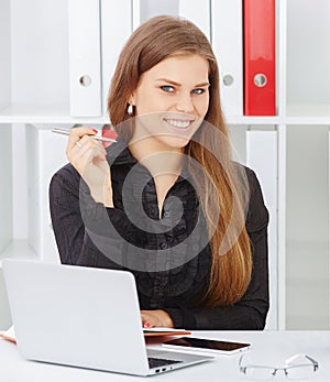 Beautiful smiling businesswoman holding pen in hand looking straight to the camera.