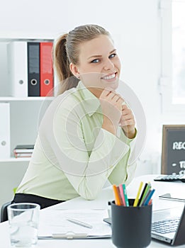 Beautiful smiling businesswoman sitting at the table with laptop in office.