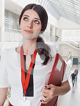 Beautiful Smiling Businesswoman Standing Against White Offices Background. Portrait of Business Woman With a Folder in Her Hands