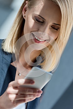beautiful smiling businesswoman using smartphone