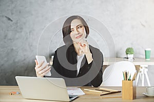 Beautiful smiling businesswoman using smartphone at workplace