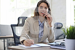 Beautiful smiling call center worker in headphones is working at modern office