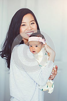 beautiful smiling Chinese Asian mother holding cute adorable newborn infant baby girl daughter.