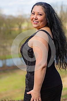 Beautiful smiling chubby middle aged Latin American woman turned looking at camera