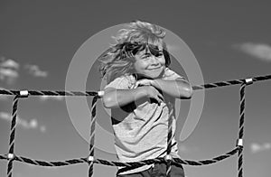 Beautiful smiling cute boy on a playground. Kids activities. Kid climbing on the net. Child sport.