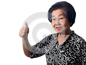 Beautiful smiling elderly asian woman raises her thumb up standing on white background. Gesture everything is okay