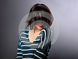 Beautiful smiling enjoing woman moving and shaking her short black hair style with red lipstick on grey background in fashion