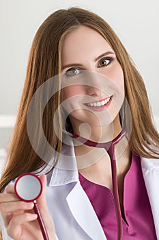 Beautiful smiling female medicine doctor holding stethoscope head ready to examine patient