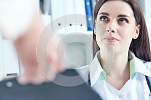 Beautiful smiling female medicine doctor listening carefully patient complaints in medical office. Medical care or