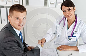 Beautiful smiling female medicine doctor shaking hands with male