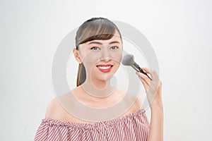 Beautiful smiling girl applying loose blush with cosmetic brush
