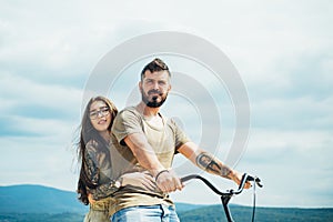 Beautiful smiling girl and bearded hipster man is riding the bicycle in the park. Couple riding bicycle on sunny day