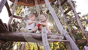 Beautiful smiling girl and boy siblings playing with ball outdoor on tree house together with their parent on sunny day