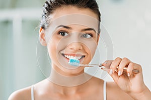 beautiful smiling girl brushing teeth photo