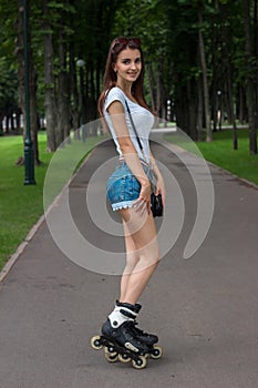 Beautiful smiling girl in denim shorts rollerblading