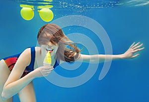 Beautiful smiling girl eating yellow ice cream underwater