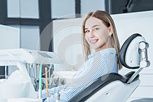 A beautiful, smiling girl examined by a dentist, is sitting in a dental chair
