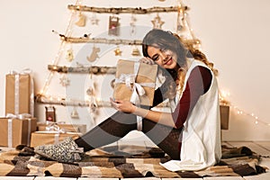 Beautiful smiling girl holding big Christmas gift over white backgound. CHRISTMAS MOOD