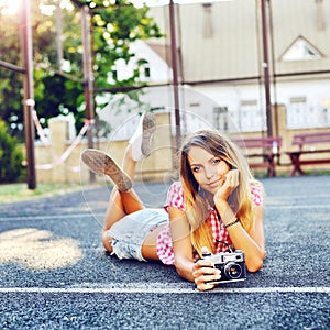 Beautiful smiling girl lying on a ground with old retro camera