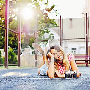 Beautiful smiling girl lying on a ground with old retro camera