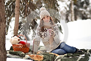 Beautiful,smiling girl sit on warm blanket in winter forest