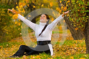 Beautiful smiling girl throwing dry leaves in the air