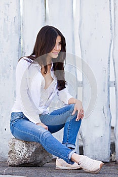 Beautiful smiling girl wearing blank white shirt and jeans posing against street wooden wall. Minimalist urban clothing