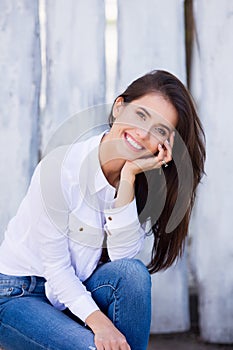 Beautiful smiling girl wearing blank white shirt and jeans posing against street wooden wall. Minimalist urban clothing