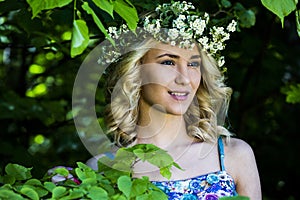 Beautiful smiling girl with a wreath on his head in the spring park