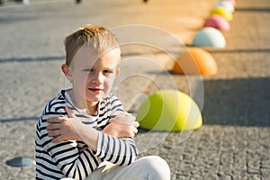 Beautiful smiling happy little boy sitting on colored stones, looking at camera