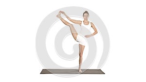 Beautiful smiling happy young woman doing yoga exercise on mat, standing in Vrksasana Posture, Tree Pose on white