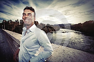 Beautiful smiling Italian man outdoors in Rome Italy. Tiber river from the bridge