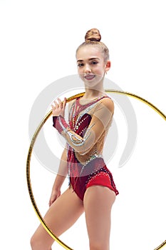 Beautiful, smiling little girl, child, rhythmic gymnast in elegant stage costume standing with gymnastic hoop against