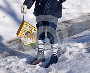 A beautiful smiling little girl holding a bird house in a park