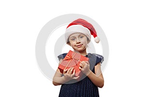 Beautiful smiling little girl in Santa Claus hat, posing with cute gift box with Christmas present, on white background