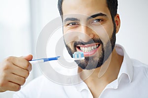 Beautiful Smiling Man Brushing Healthy White Teeth With Brush. H