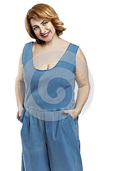 Beautiful smiling middle aged woman with red hair in denim overalls. Self-care and health. Isolated on white background. Vertical