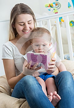 Beautiful smiling mother reading story to her 9 months old baby