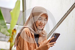 a beautiful smiling Muslim woman playing social media from low angle