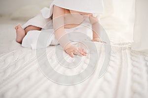 Beautiful smiling newborn baby boy covered with white bamboo towel with fun ears. Sitting on a white knit, wool plaid bright inter