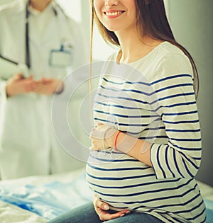 Beautiful smiling pregnant woman with the doctor at hospital