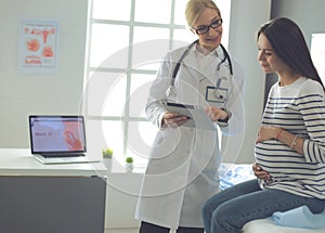 Beautiful smiling pregnant woman with the doctor at hospital