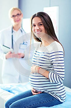 Beautiful smiling pregnant woman with the doctor at hospital