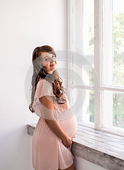 Beautiful smiling pregnant woman is holding belly