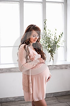 Beautiful smiling pregnant woman is holding belly