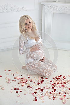 Beautiful smiling pregnant woman sitting on floor with red rose