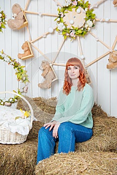 Beautiful smiling redhaired woman sitting on the haystack